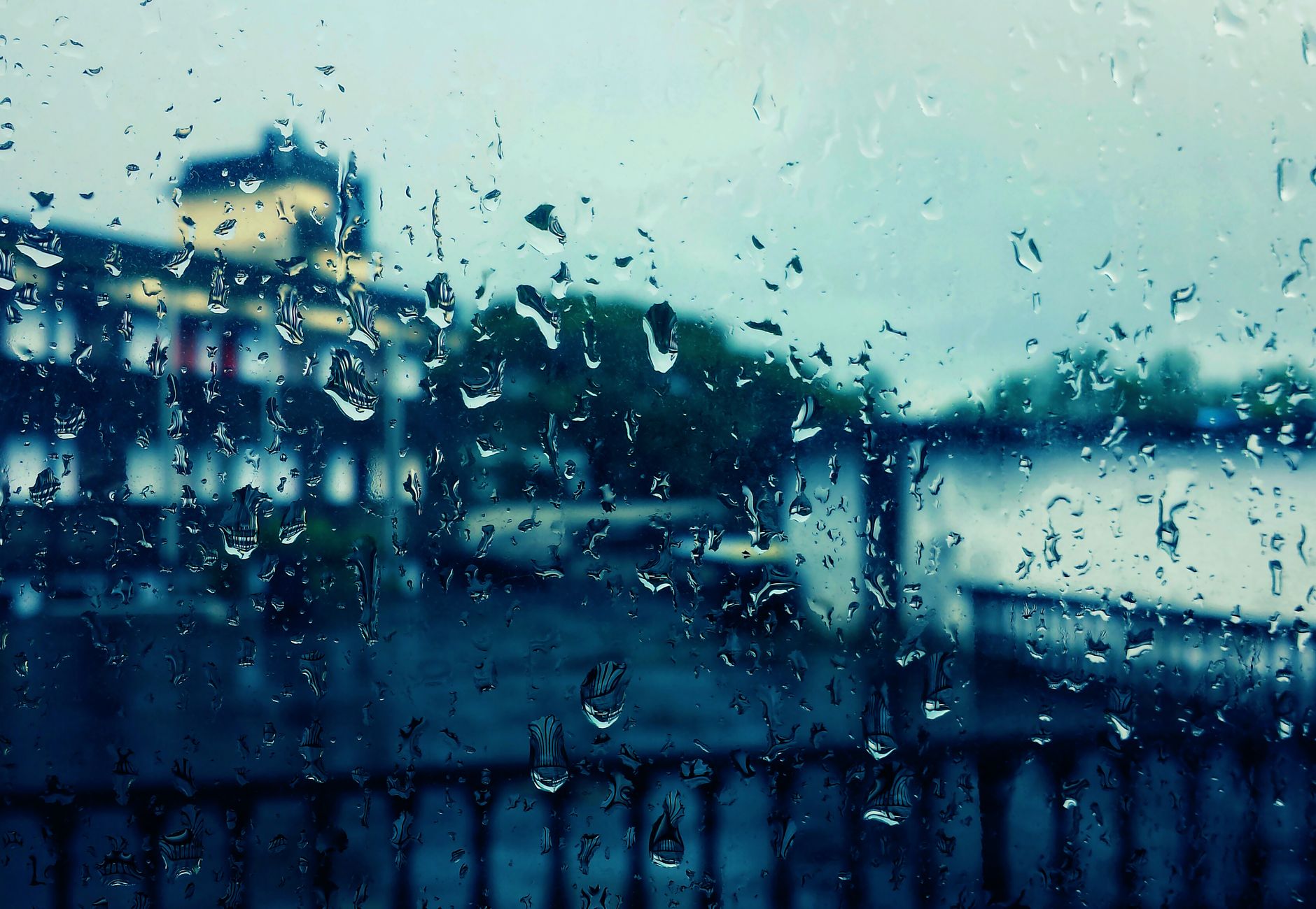 Artistic view through a rain-soaked window capturing blurred cityscape in the background.