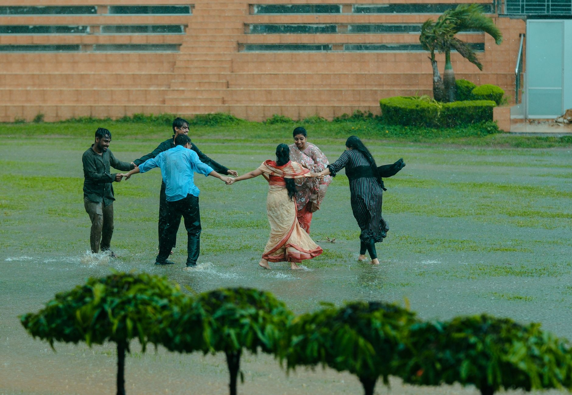 Group of adults enjoying a rain dance on a green lawn, embracing vibrant joy.