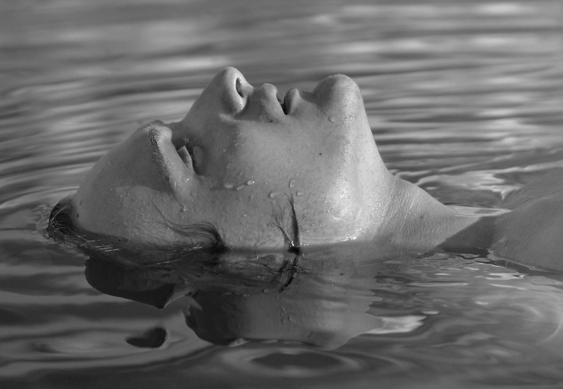 Black and white portrait of an adult woman floating peacefully in water.