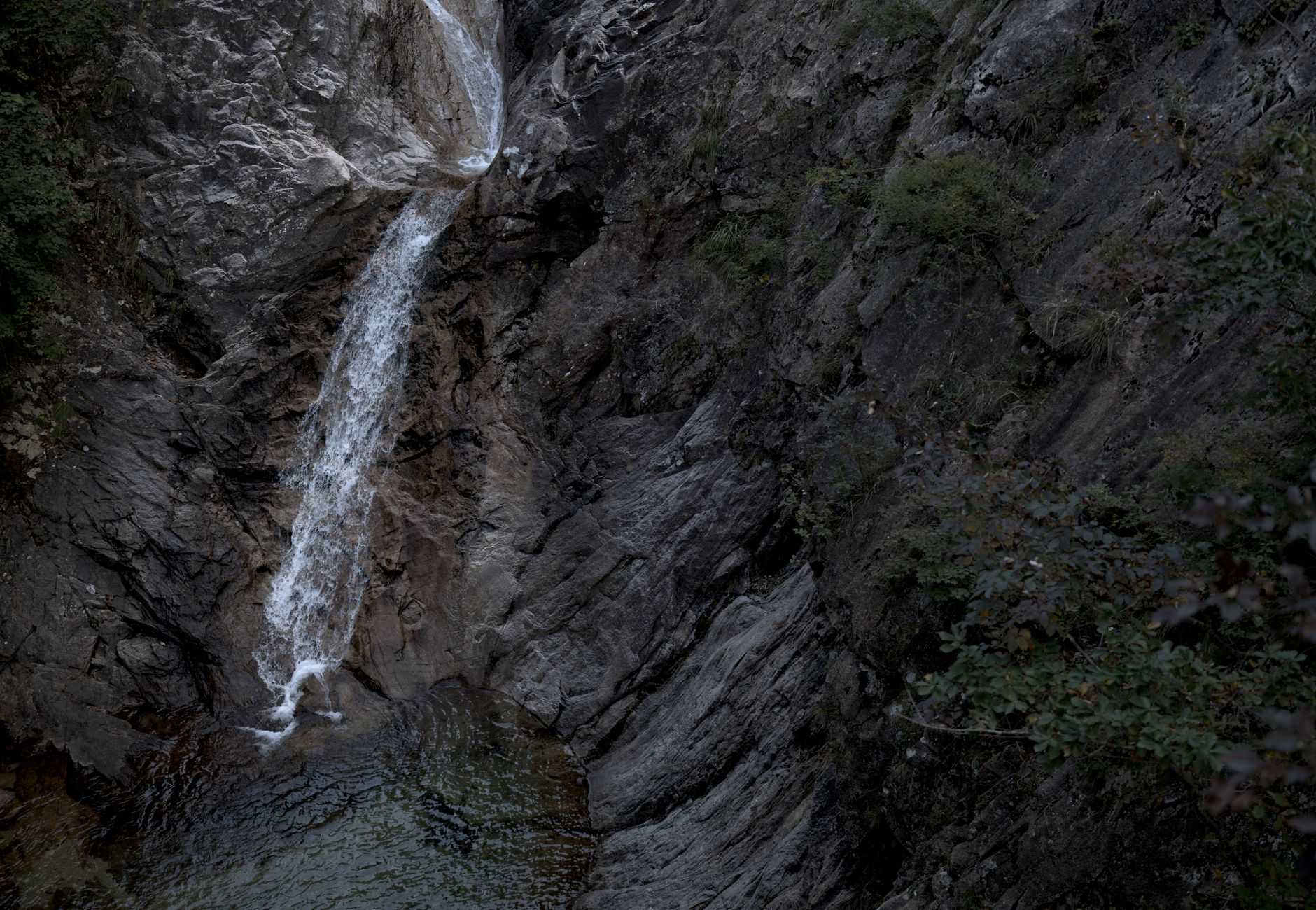 A beautiful waterfall cascading over rocky cliffs, surrounded by lush greenery.