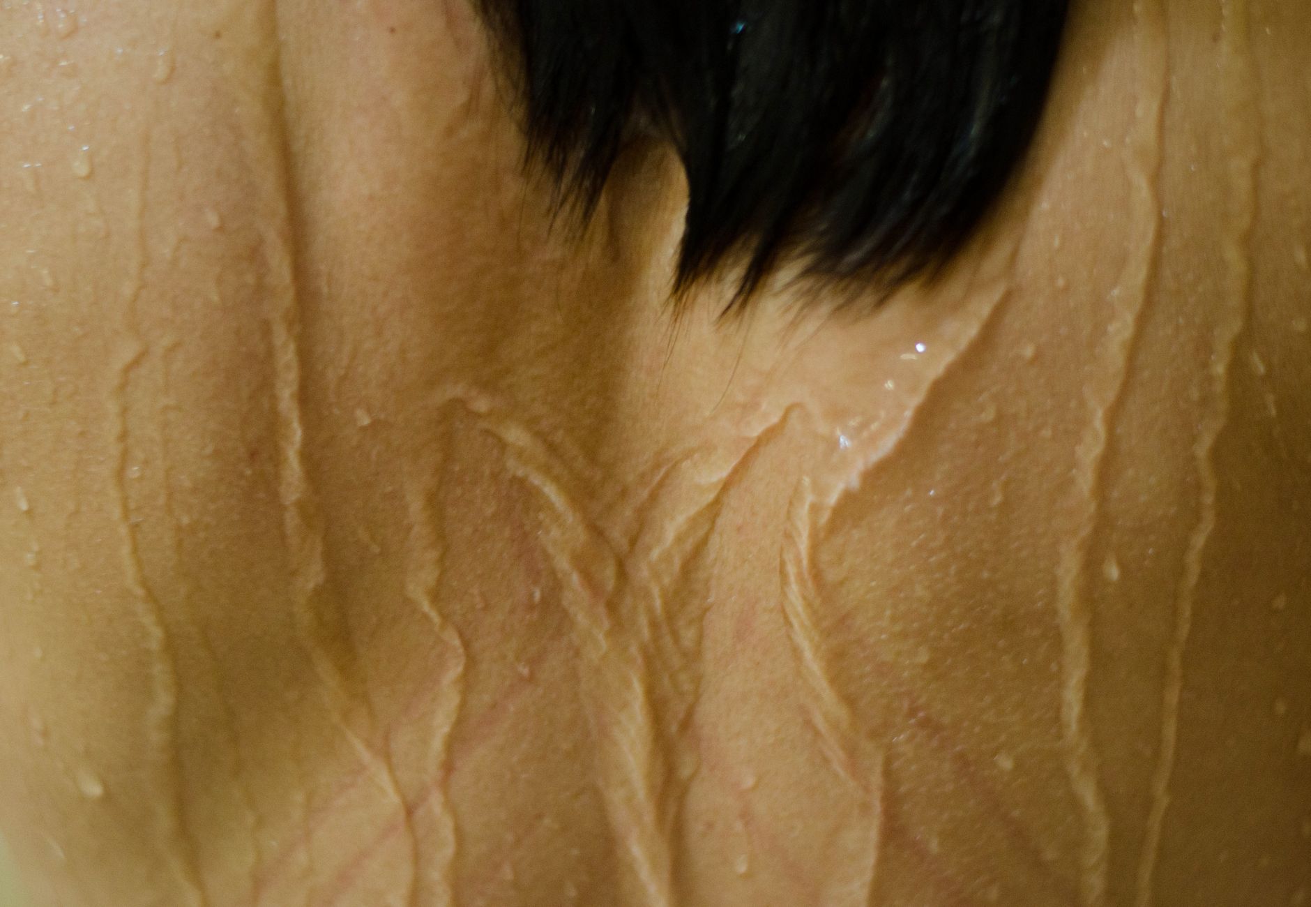 Detailed view of water droplets on skin with dark hair. Captured in Natal, Brazil.