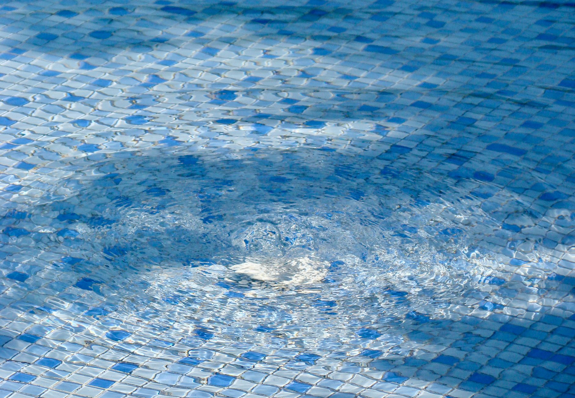 Close-up of textured pool water with rippling effect on tiles.
